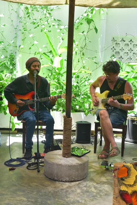 Two guitarists playing under a parasol in the green garden café