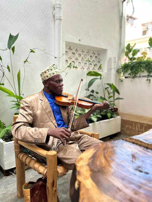 Musician in a kofia playing violin in the café courtyard