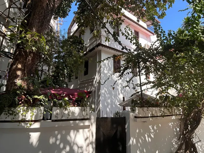 White house on Shangani behind trees and a planted wall