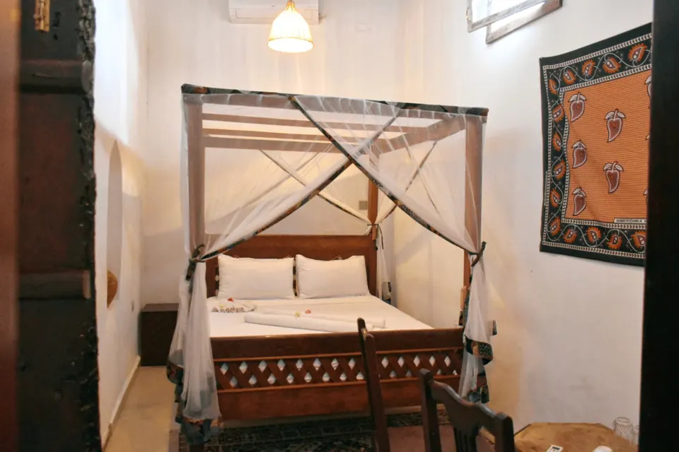 Dalasini Double room with a four-poster bed, mosquito net and kanga wall hanging