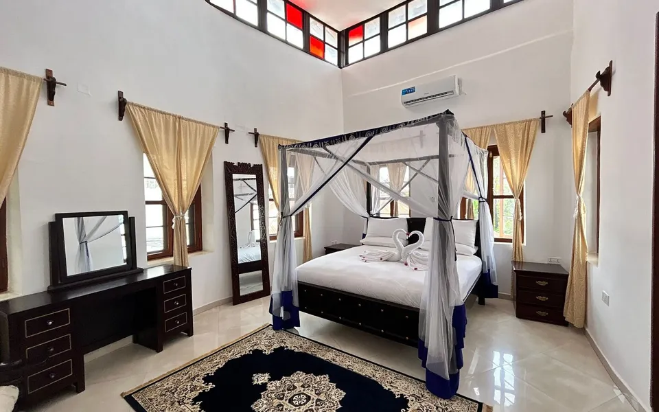 Tanzanite Master Suite with a king four-poster bed under stained-glass clerestory windows