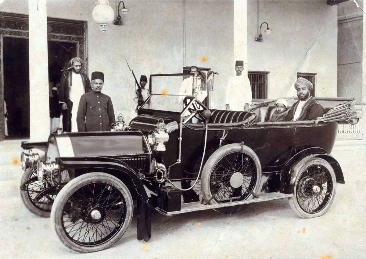 Vintage photo of an early open-top motorcar with men standing beside it