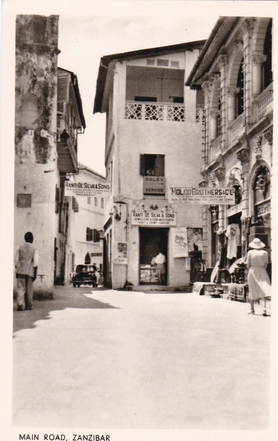 Vintage black and white photo of Main Road, Zanzibar, with shop signs and people walking