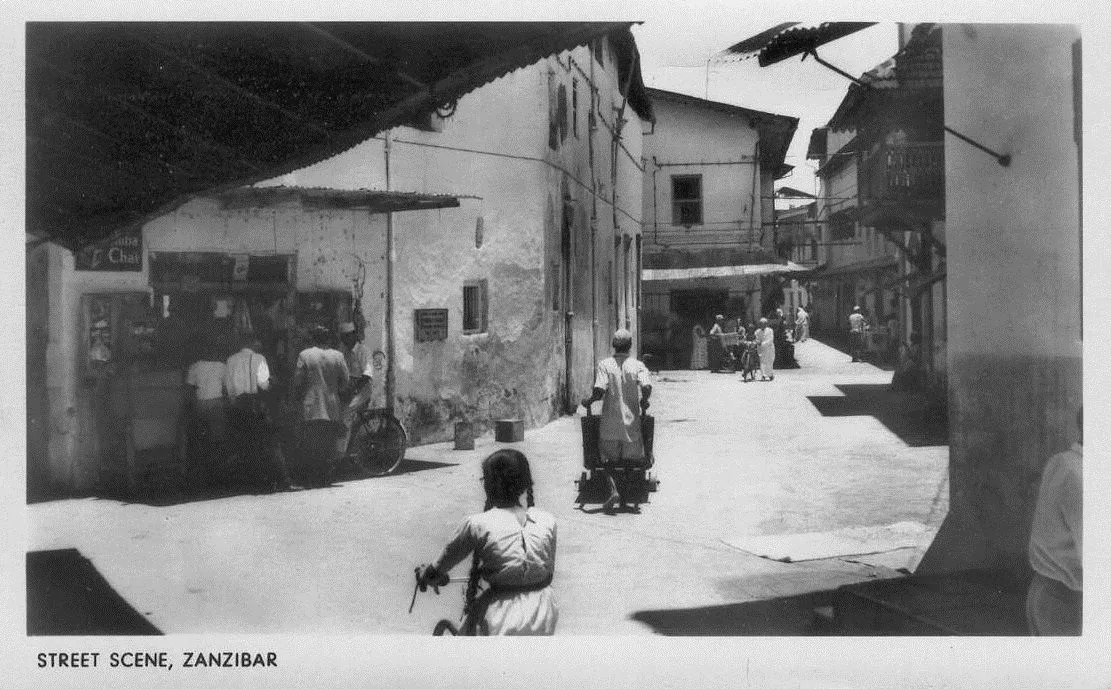 Vintage photo of a Stone Town street corner with shops and cyclists